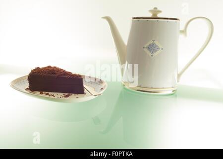 Ein Kuchen, Schokolade und einer Teekanne auf einem Tisch grünes Licht aus. Stockfoto