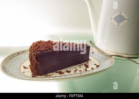 Ein Kuchen, Schokolade und einer Teekanne auf einem Tisch grünes Licht aus. Stockfoto