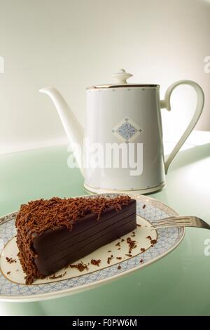 Ein Kuchen, Schokolade und einer Teekanne auf einem Tisch grünes Licht aus. Stockfoto