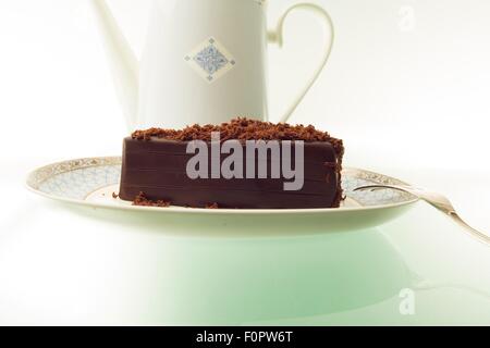 Ein Kuchen, Schokolade und einer Teekanne auf einem Tisch grünes Licht aus. Stockfoto