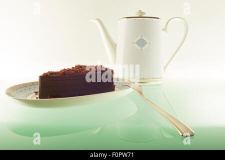 Ein Kuchen, Schokolade und einer Teekanne auf einem Tisch grünes Licht aus. Stockfoto