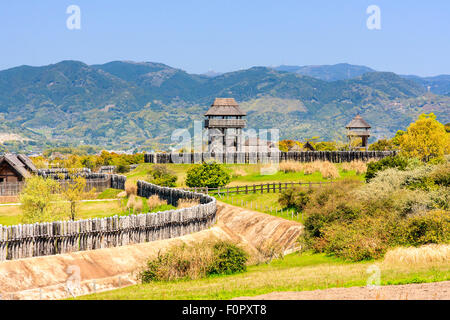 Japan, Yoshinogari Eisenzeit Historical Park. Rekonstruierte Yayoi Gehäuse. Äußere Holz- beteiligung Defensive Wall mit Graben und Wachtürme. Stockfoto