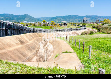 Japan, Yoshinogari Eisenzeit Historical Park. Rekonstruierte Yayoi Gehäuse. Äußere Holz- beteiligung Defensive Wall mit Graben und Wachtürme. Stockfoto