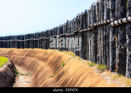 Japan, Yoshinogari Eisenzeit Historical Park. Rekonstruierte Yayoi Gehäuse. Äußere Holz- beteiligung Verteidigungsmauer mit dugout Graben. Stockfoto