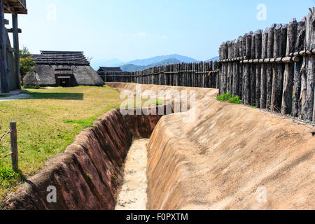 Japan, Yoshinogari Eisenzeit Historical Park. Rekonstruierte Yayoi Gehäuse. Äußere Holz- beteiligung Verteidigungsmauer mit dugout Graben. Stockfoto