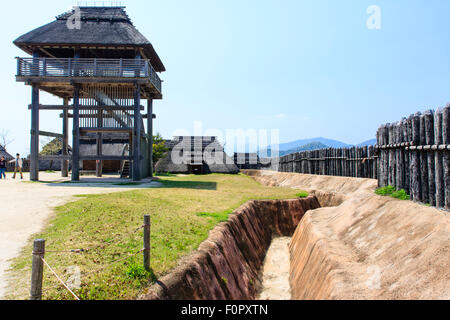 Japan, Yoshinogari Eisenzeit Historical Park. Rekonstruierte Yayoi Gehäuse. Äußere Holz- beteiligung Verteidigungsmauer mit dugout Graben. Stockfoto