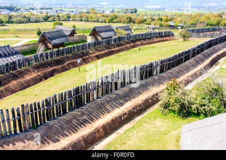 Japan, Yoshinogari Historical Park. Rekonstruierte Yayoi Dorf, Kura-zu-ichi, mit Lagerhäusern auf dem Markt hinter Holz- Verteidigung Wand. Stockfoto