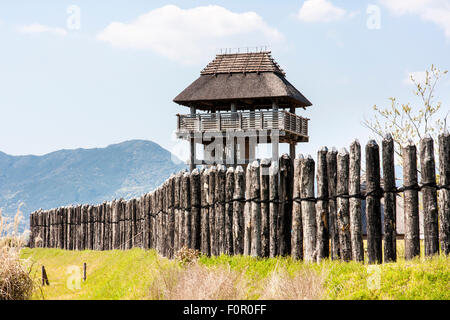 Japan, Yoshinogari Historical Park. Yayoi Minami-Naikaku, South inneren Palast Holz- Watch Tower und hölzernen Pfahl Mauer rekonstruiert. Blue Sky. Stockfoto