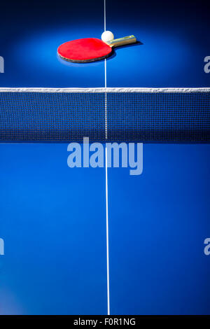 Tischtennis-Schläger und Ball im Rampenlicht auf blauen Ping-Pong-Tisch angezeigt. Stockfoto