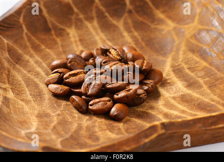 Handvoll Kaffeebohnen in Holzschale Stockfoto