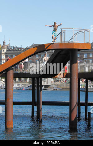 Boy Springen von der Kalvebod Bølge, Kalvebod Wellen oder Welle, in Kalvebod Brygge im inneren Hafen von Kopenhagen. Social Hub, Veranstaltungsort für Wassersport Stockfoto