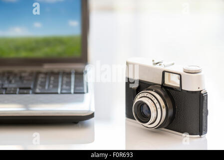 35mm Vintage Fotokamera auf weißen Tisch in der Nähe von notebook Stockfoto