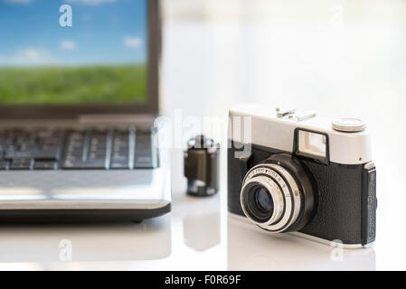 35mm Vintage Fotokamera auf weißen Tisch in der Nähe von Notebook und film Stockfoto