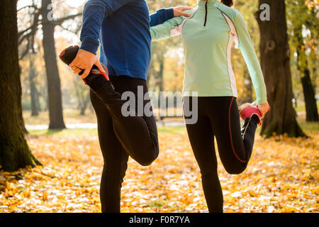 Detail von Mann und Frau dehnen Beine vor dem Joggen im Herbst Natur Stockfoto