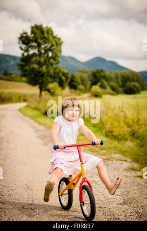 Kleines Kind fahren ihr Fahrrad Tannen auf Landstraße Outdor in der Natur Stockfoto