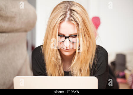 Frau am Laptop zu Hause eingeben Stockfoto