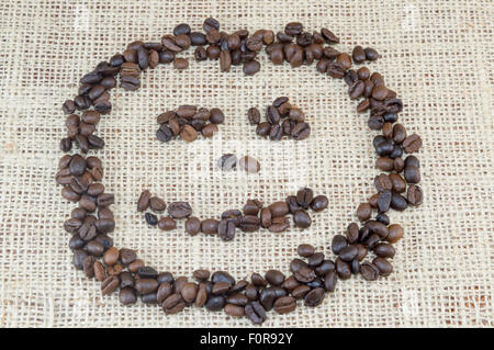 Smiley-Gesicht, hergestellt ausschließlich aus Kaffeekörner auf Kaffee Tasche Textur gelegt Stockfoto