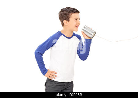 Studioaufnahme eines niedlichen kleinen Jungen sprechen durch eine Blechdose Telefon isoliert auf weißem Hintergrund Stockfoto