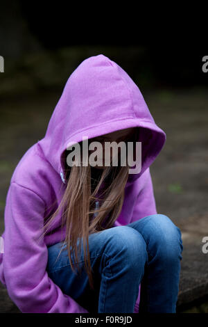Trauriges Mädchen in Kapuzenshirt, sitzen mit Kopf niedrig in Verzweiflung Stockfoto