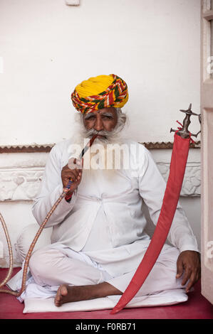 Jodhpur, Indien. Mehrangarh Sandstein Wallburg der Marwar Herrscher. Ein Mann in traditioneller Kleidung eine Shisha Wasserpfeife. Stockfoto