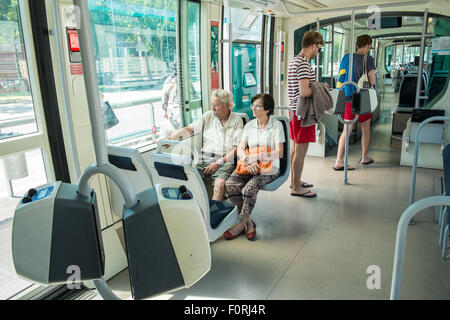 Touristen und Einheimische und Innere des lokalen oben Boden u-Bahn Straßenbahn, Zug in Katalanisch Olimpic District, Barcelona, Katalonien, Spanien Stockfoto