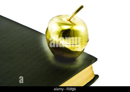 Goldener Apfel auf alten Black Book isoliert auf weiss Stockfoto