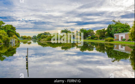 Lake with sky and trees reflecting in the water at Mewsbrook Park, Littlehampton, West Sussex, England, UK. Stockfoto