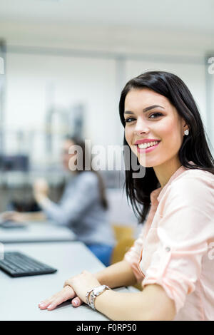 Junge schöne Frau glücklich lächelnd in einem Klassenzimmer mit Computern ausgestattet Stockfoto