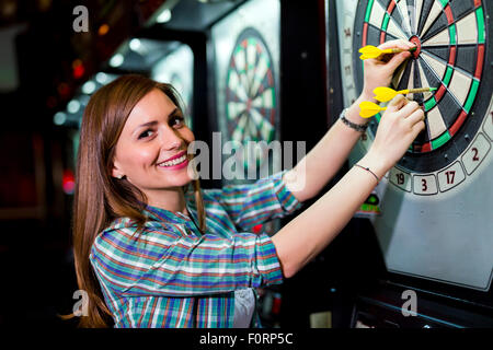 Junge schöne Frau in einem Club Dart spielen und Lächeln Stockfoto