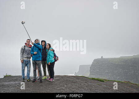 Gruppe von Personen, die eine Selfie mit einem Selfie-Stick an den Cliffs of Moher in Irland Stockfoto