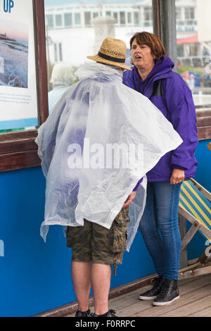 Bournemouth, Dorset, Großbritannien. 20. August 2015. Festivalmacher des Bournemouth Air Festivals halten sich bei schlechtem Wetter unter Schutz am Pier und tragen einen Plastikponcho zum Schutz vor Regen. Quelle: Carolyn Jenkins/Alamy Live News Stockfoto