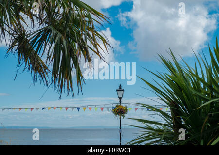 Eine Aufnahme in Penarth Strandpromenade von einer traditionellen Straßenleuchte, Wimpel, Blumen und mediterranen Pflanzen. Stockfoto