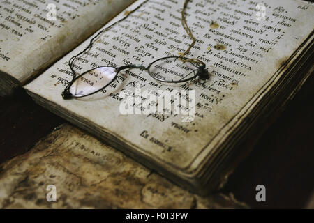 altes Buch und Brille auf seinen Seiten liegend Stockfoto