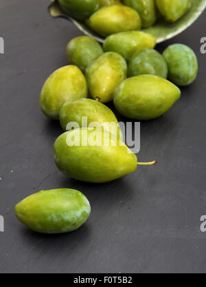 grüne Pflaumen auf schwarze Schieferoberfläche Stockfoto