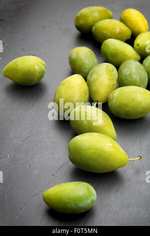 grüne Pflaumen auf schwarze Schieferoberfläche Stockfoto