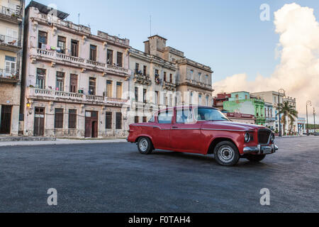 Rote alte amerikanische Auto auf der Straße in den Malecon in Havanna Kuba vor Pastell Schatten Gebäude reparaturbedürftig Stockfoto