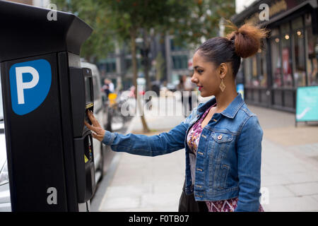 junge Frau, die ihr Parkticket bezahlen Stockfoto