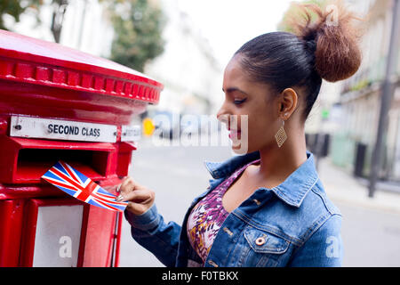 junge Frau, die Entsendung einer Postkarte in London Stockfoto