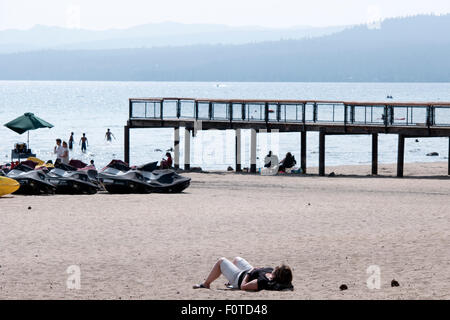 Lake Tahoe, CA, USA. 20. August 2015. Eine Frau liegt am Strand in der Nähe von einem Pier von stark niedrigen Wasserständen am Lake Tahoe während der anhaltenden historischen California Dürre ausgesetzt. Gouverneur Jerry Brown erklärt ein "State of Emergency" Anfang dieses Jahres und schweren Wassers Nutzungsbeschränkungen erlassen. Bildnachweis: Jonathan Alcorn/ZUMA Draht/Alamy Live-Nachrichten Stockfoto