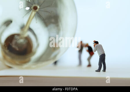 Kreative Idee-Konzept - Miniatur-Fotograf mit Vintage Glühbirne auf offene Notizbuch Stockfoto