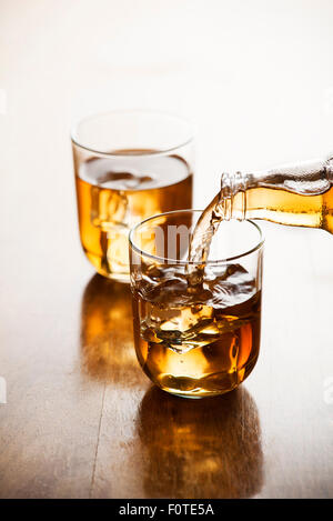 Eistee im Glas mit Eiswürfeln gießen. Stockfoto