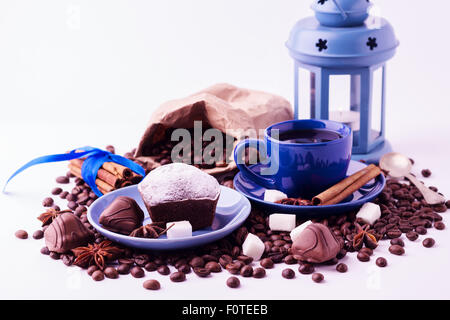 Kaffee-Konzept isoliert auf weißem Hintergrund. Tasse Kaffee und einen kleinen Kuchen auf den Körnern. Stockfoto