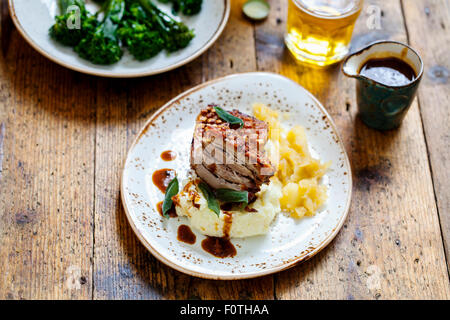 Schweinebauch mit knisternden, Kartoffelpüree, Apfelmus und tief gebratene Salbeiblätter Stockfoto