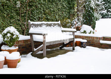 Schneebedeckte Gartenbank auf einer Terrasse im winter Stockfoto