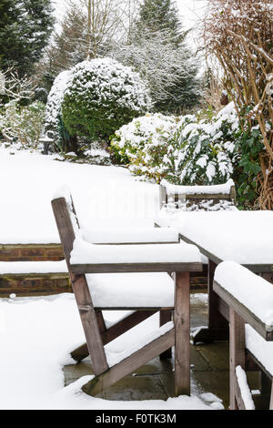 Schneebedeckte Patio-Möbel in einem Garten im winter Stockfoto