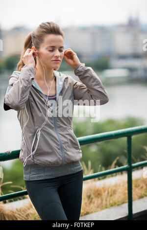 Finden Sie diese schlagen, dass die Motivation... Eine Frau hält ihre Ohrhörer in ihre Ohren, Augen geschlossen, und verlor in den Rhythmus ihrer musi Stockfoto