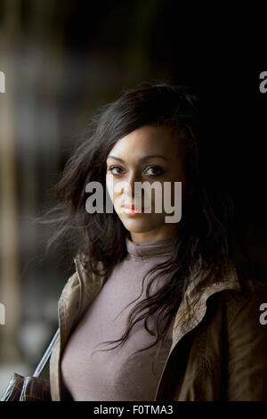 Low-Key natürliche Licht Porträt junge dunkelhäutige Frau in Norwich Cathedral Kreuzgängen. Stockfoto