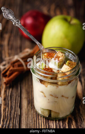 Parfait-Stil gesunde geschichteten Snack oder Dessert mit Joghurt und Apfel mit Zimt im Glas auf Holztisch. Stockfoto