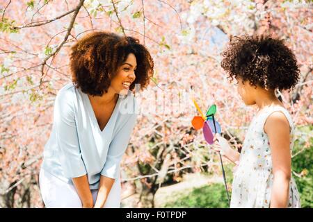 Mutter lächelte Tochter halten bunte Windrad Spielzeug Stockfoto