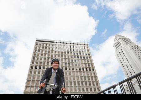 Niedrigen Winkel Ansicht der Geschäftsmann Radfahren, Los Angeles City Hall, Kalifornien, USA Stockfoto